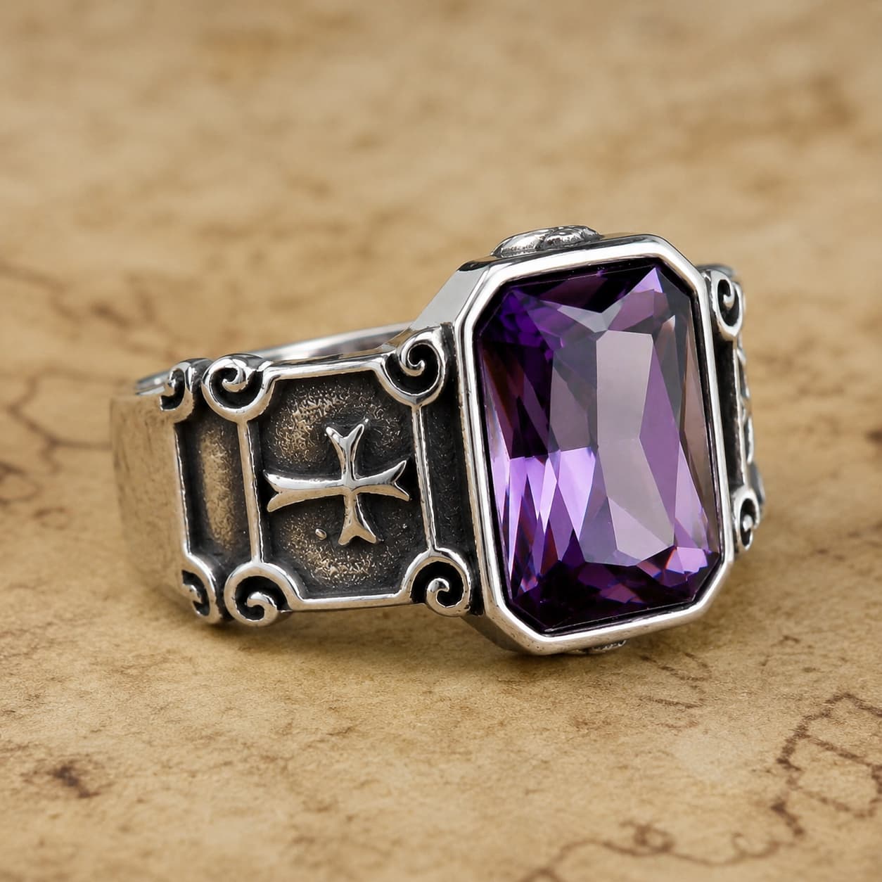 Bague Croisée de Lumière en acier inoxydable avec pierre violette posée sur un parchemin ancien