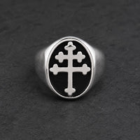 Bague Croix de Lorraine en acier inoxydable argenté avec croix blanche sur fond noir, posée sur pierre sombre