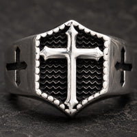 Gros plan de la Bague Croix Impériale en acier inoxydable avec croix blanche en relief sur fond noir ondulé