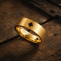 Bague Croix Pattée du Templier en acier inoxydable doré posée sur bois médiéval