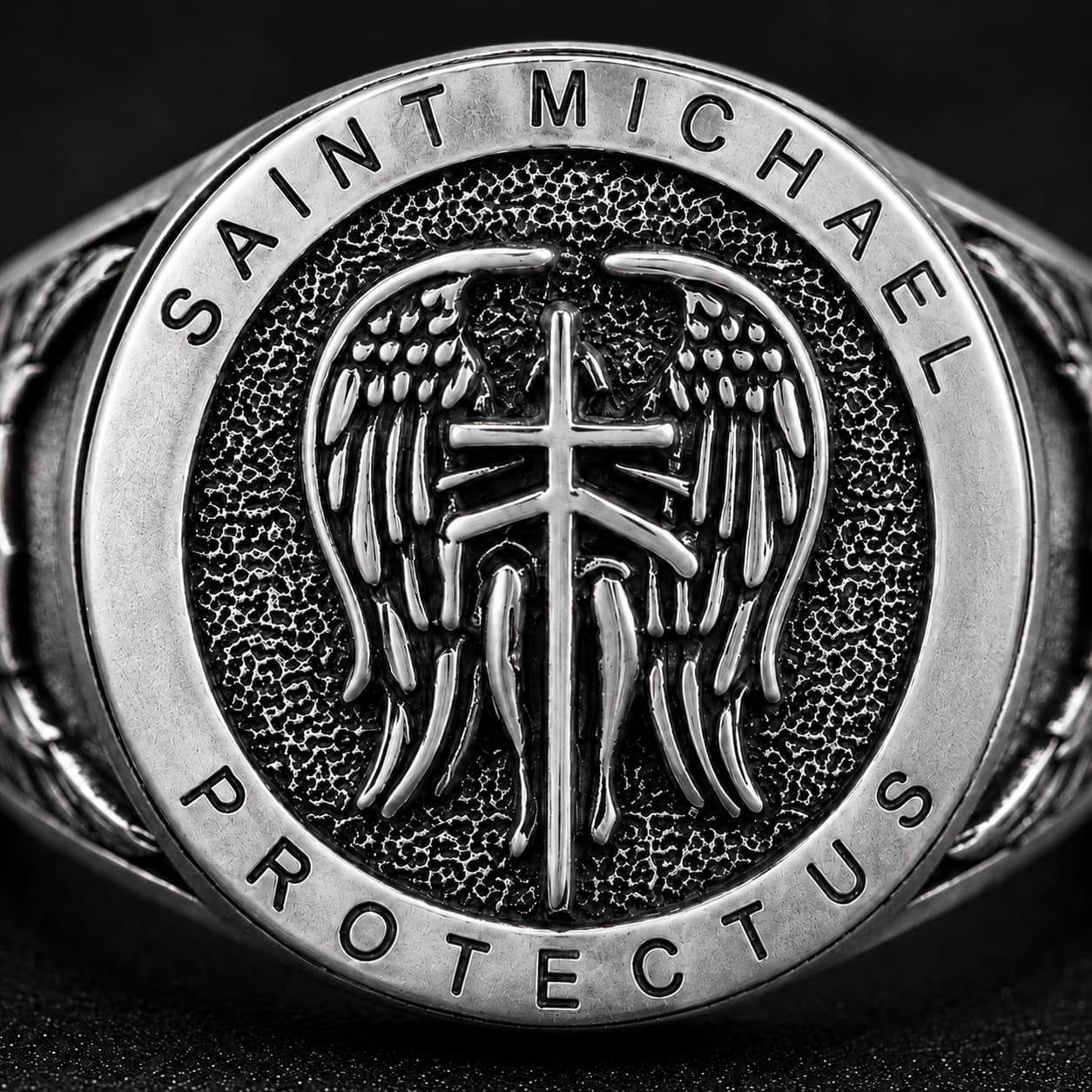 Gros plan de la Bague de la Prière de l’Archange en argent 925 sterling avec ailes, croix et inscription Saint Michael Protect Us