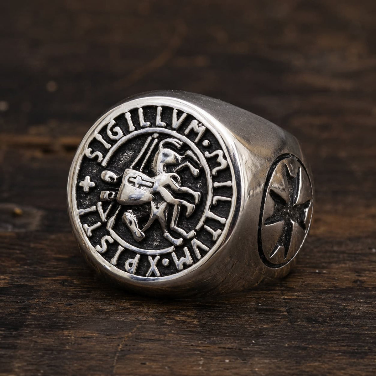 Bague du Chevalier en acier inoxydable avec sceau templier et inscription Sigillum Militum Xpisti posée sur bois rustique