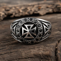 Bague du Commandeur Croisé en acier inoxydable avec croix templière et détails noirs, posée sur bois rustique