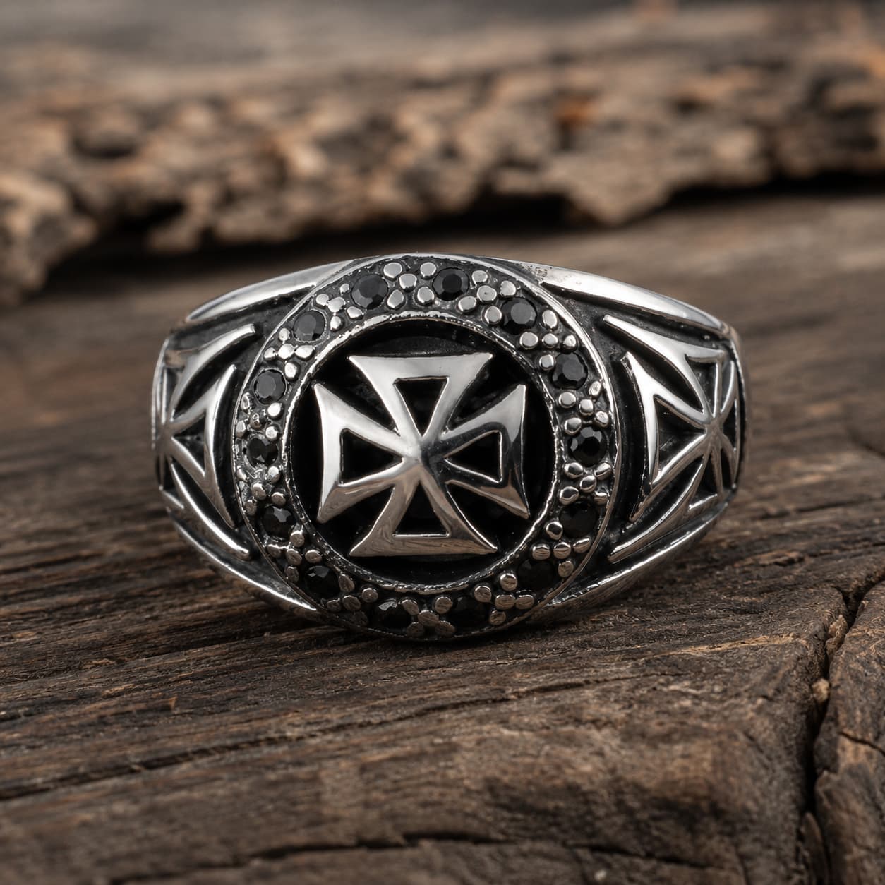Bague du Commandeur Croisé en acier inoxydable avec croix templière et détails noirs, posée sur bois rustique