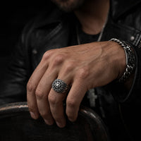 Bague du Commandeur Croisé en acier inoxydable portée à la main par un homme avec veste en cuir noire