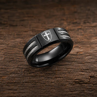 Bague de l’Écuyer en acier inoxydable noire avec croix templière sur bouclier posée sur bois rustique