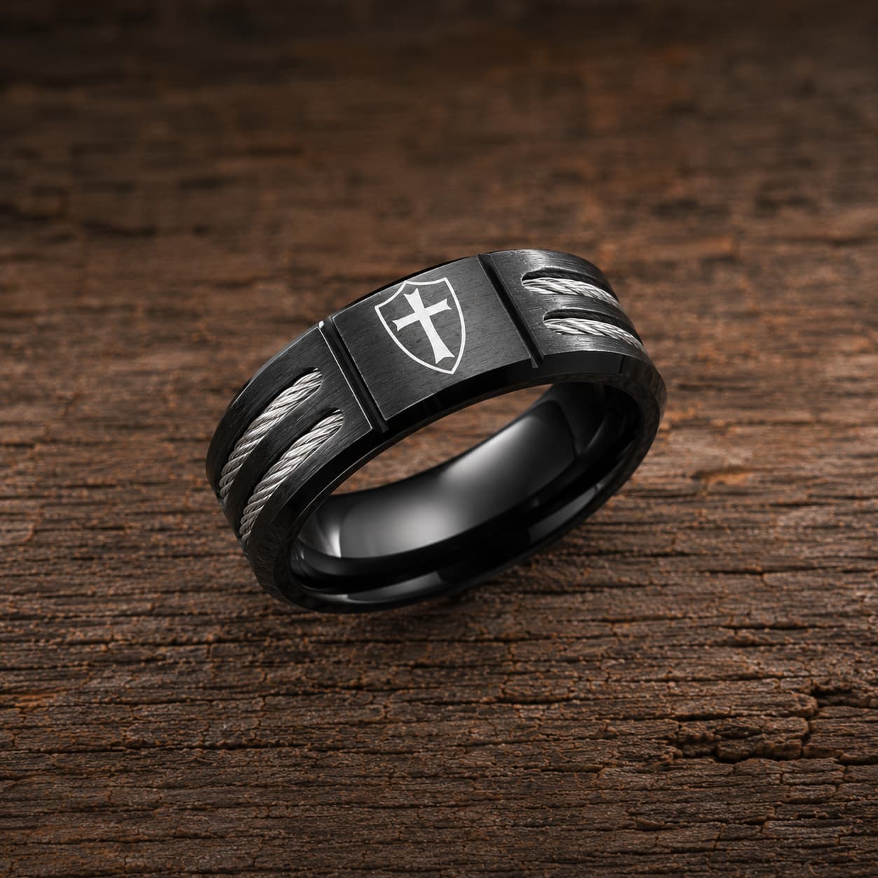 Bague de l’Écuyer en acier inoxydable noire avec croix templière sur bouclier posée sur bois rustique