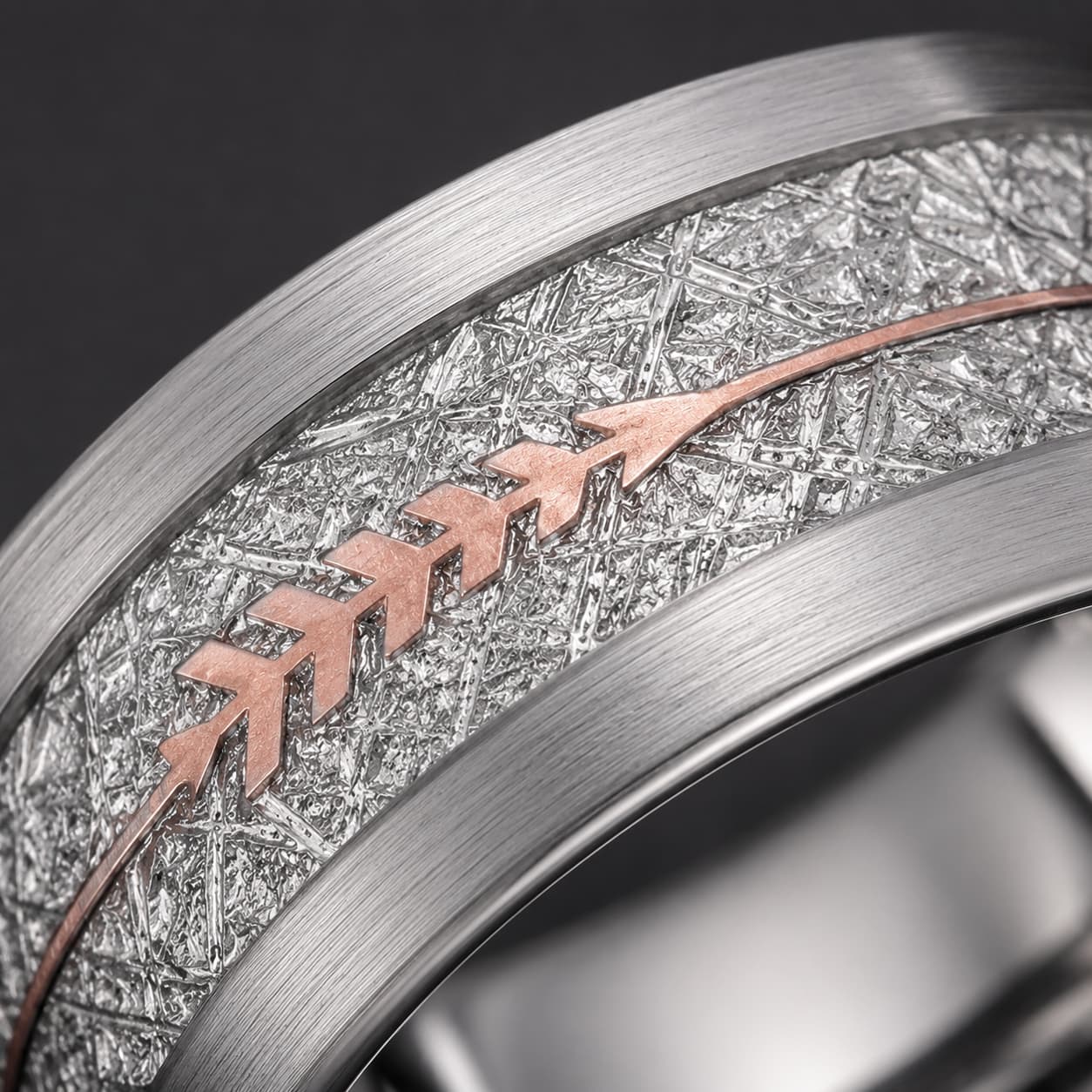 Bague Flèche Sacrée en tungstène en gros plan avec motif flèche rose sur surface texturée