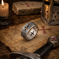 Bague de la Foi Éternelle en acier inoxydable présentée dans un décor médiéval avec parchemin, épée, casque et bougie