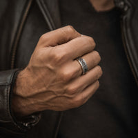 Bague de la Foi Éternelle en acier inoxydable portée à la main par un homme avec veste en cuir noire