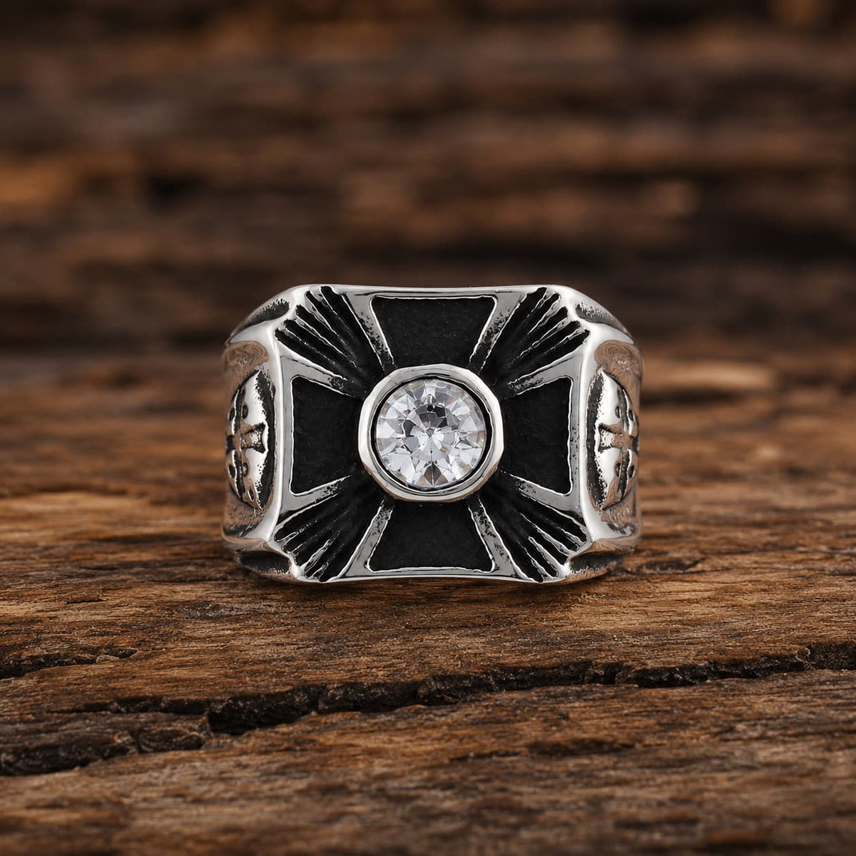 Bague Héritage des Croisés en acier inoxydable avec croix noire, pierre centrale brillante et finition argentée sur bois rustique