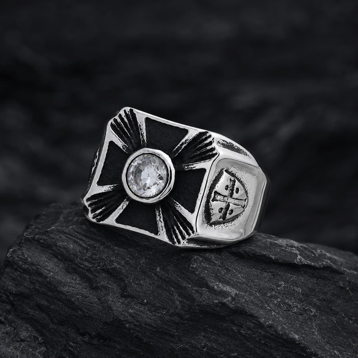 Bague Héritage des Croisés en acier inoxydable posée sur pierre noire avec croix noire, pierre centrale et détails argentés