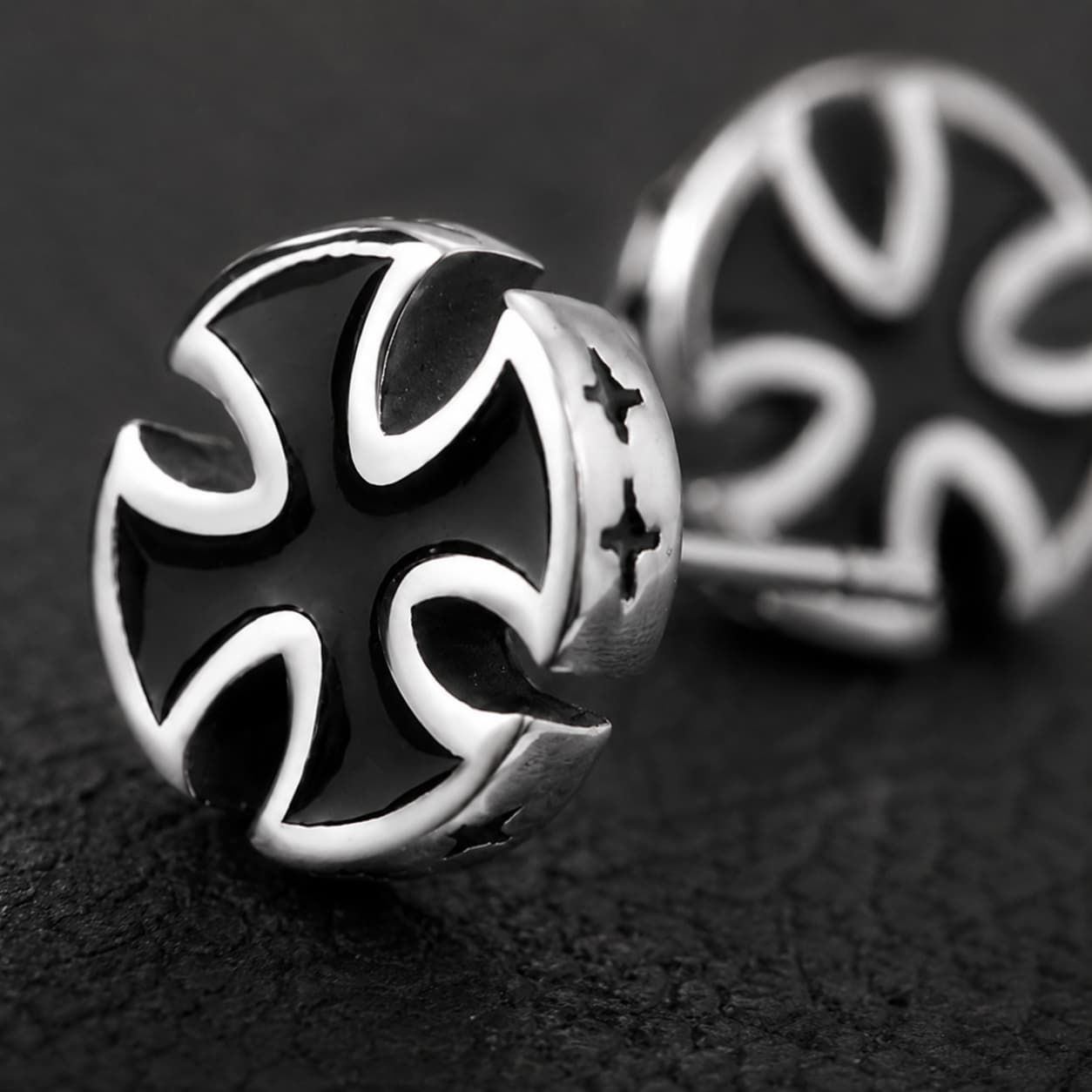 Gros plan des Boucles d’Oreilles Croix du Fief en acier inoxydable montrant la croix noire et les contours argentés.
