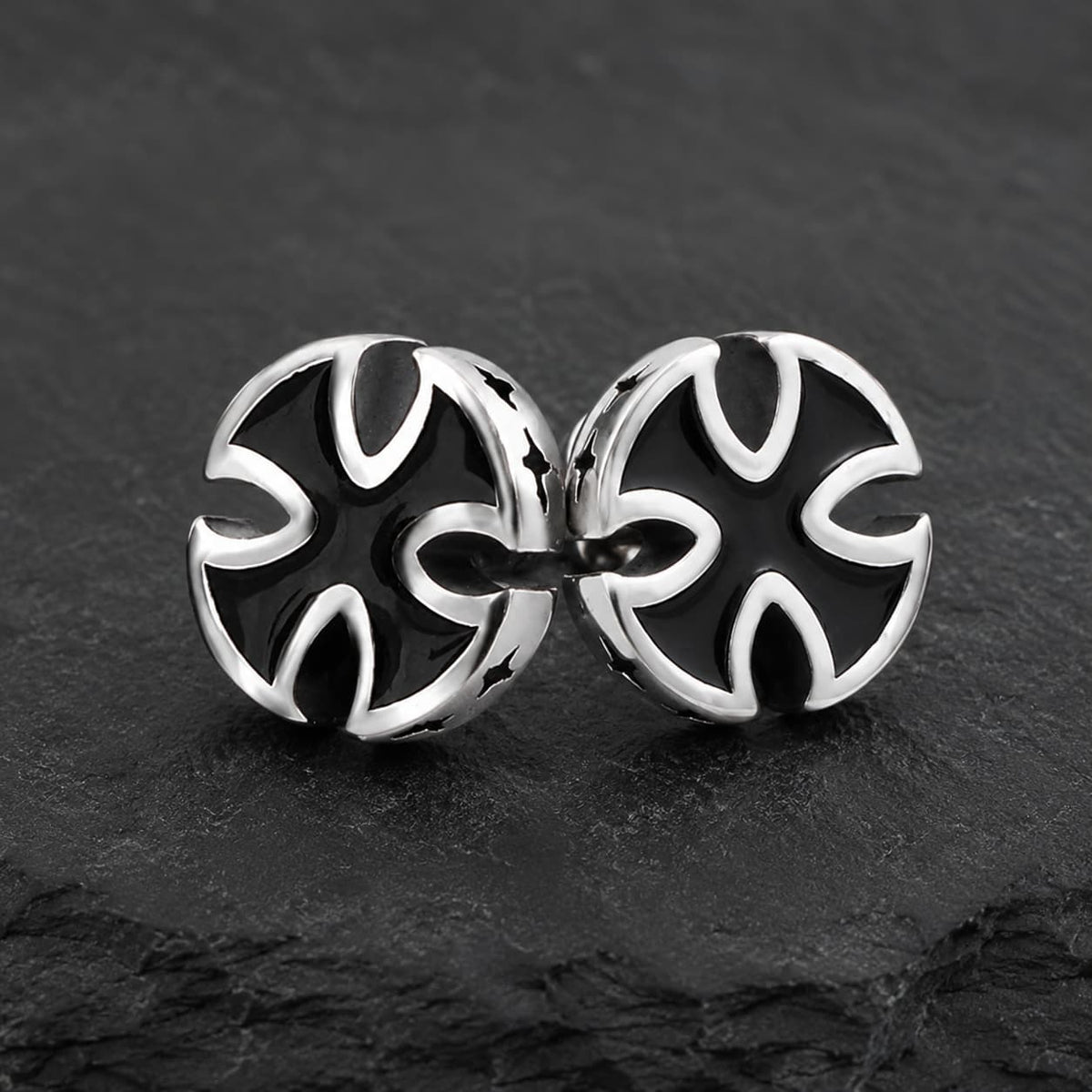 Boucles d’Oreilles Croix du Fief en acier inoxydable avec croix noire et argentée sur ardoise sombre.