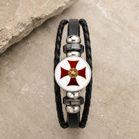 Bracelet Croix du Temple en cuir tressé noir avec médaillon croix rouge et or en alliage métallique premium sur pierre médiévale claire