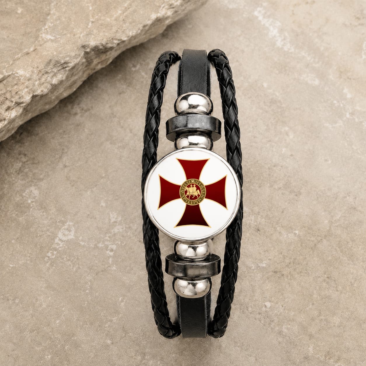 Bracelet Croix du Temple en cuir tressé noir avec médaillon croix rouge et or en alliage métallique premium sur pierre médiévale claire