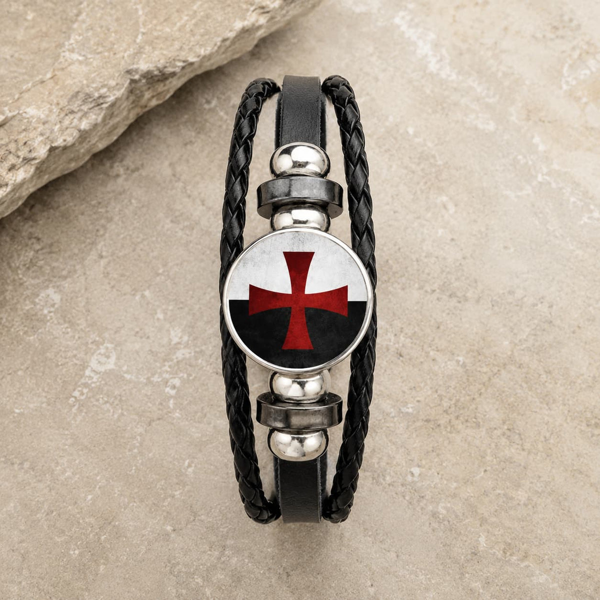 Bracelet Croix du Temple en cuir tressé noir et alliage métallique premium sur pierre médiévale claire