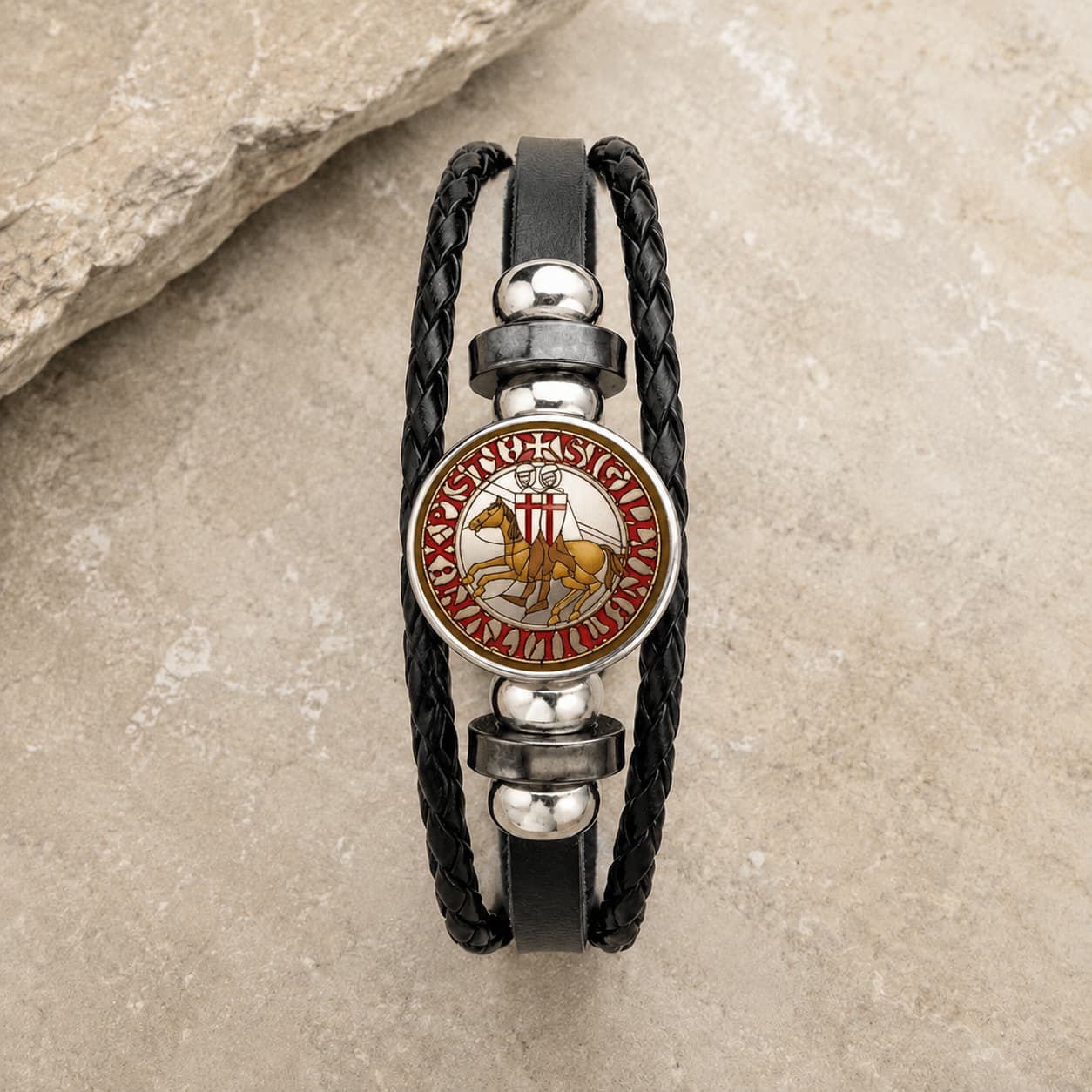 Bracelet Croix du Temple en cuir tressé noir avec médaillon sceau templier rouge et or en alliage métallique premium sur pierre médiévale claire