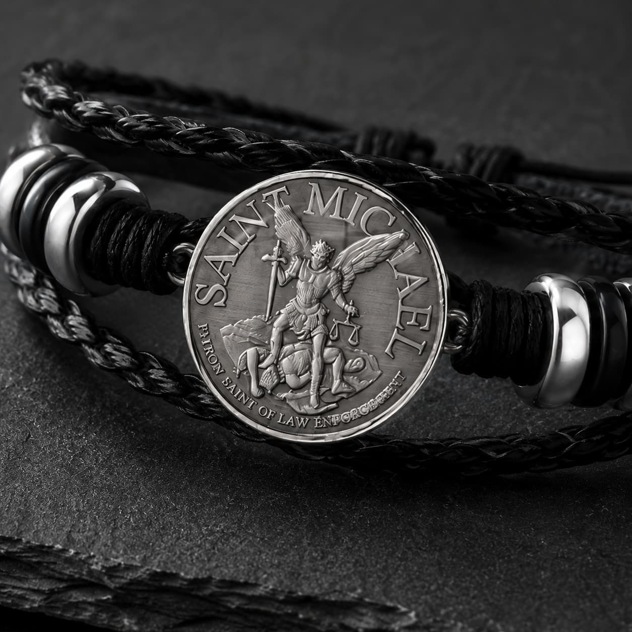 Gros plan du Bracelet de l’Archange Protecteur avec médaille Saint Michel argentée, cuir tressé noir et détails métalliques