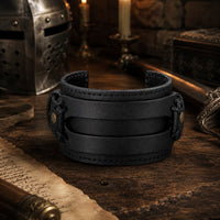 Bracelet de la Vaillance du Croisé en cuir véritable noir dans un décor médiéval avec casque, épée, parchemin et lumière chaude