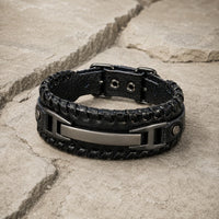 Bracelet de la Volonté du Croisé en cuir premium noir et alliage métallique renforcé présenté en vue 3/4 sur pierre médiévale claire