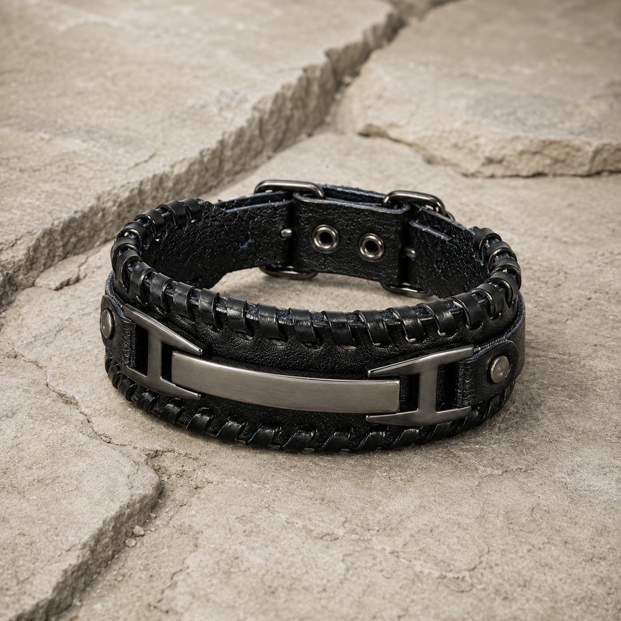 Bracelet de la Volonté du Croisé en cuir premium noir et alliage métallique renforcé présenté en vue 3/4 sur pierre médiévale claire