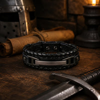 Bracelet de la Volonté du Croisé en cuir premium noir dans un décor médiéval avec casque, épée, parchemin, bois ancien et lumière chaude