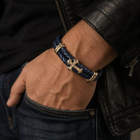 Homme portant le Bracelet du Commandeur Sacré en cuir premium bleu marine avec croix dorée et acier inoxydable.