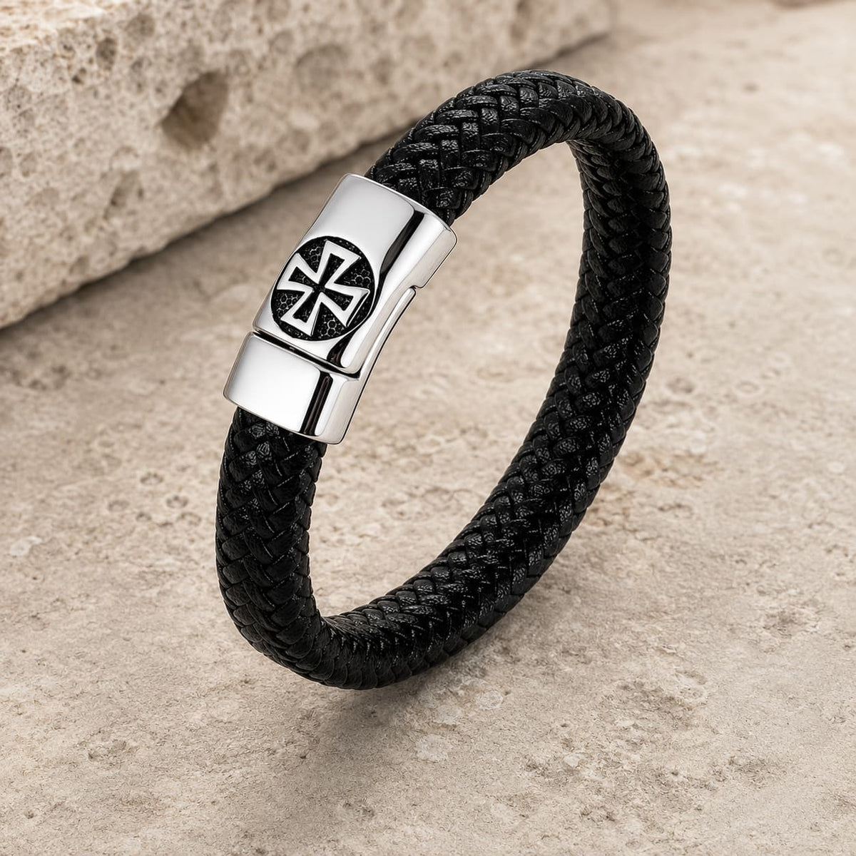 Bracelet de l’Élévation en cuir tressé noir et acier inoxydable sur pierre médiévale claire