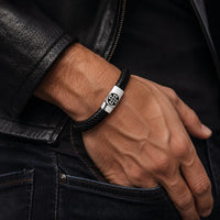 Bracelet de l’Élévation porté au poignet par un homme avec cuir tressé noir et acier inoxydable