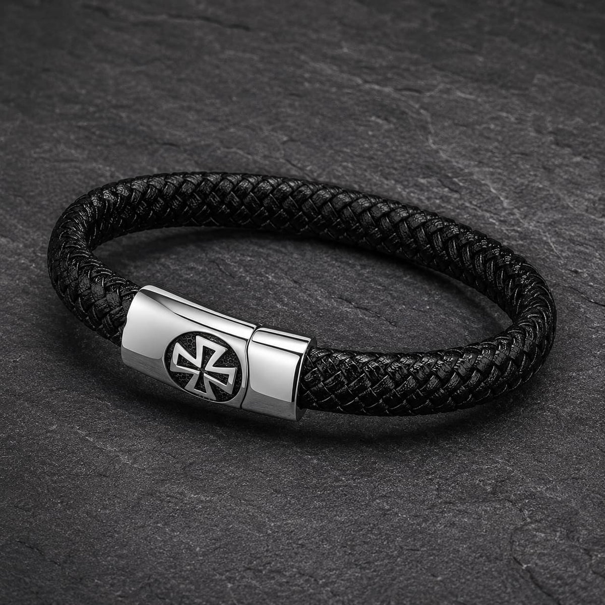 Vue angle 3/4 du Bracelet de l’Élévation en cuir tressé noir et acier inoxydable sur fond anthracite texturé