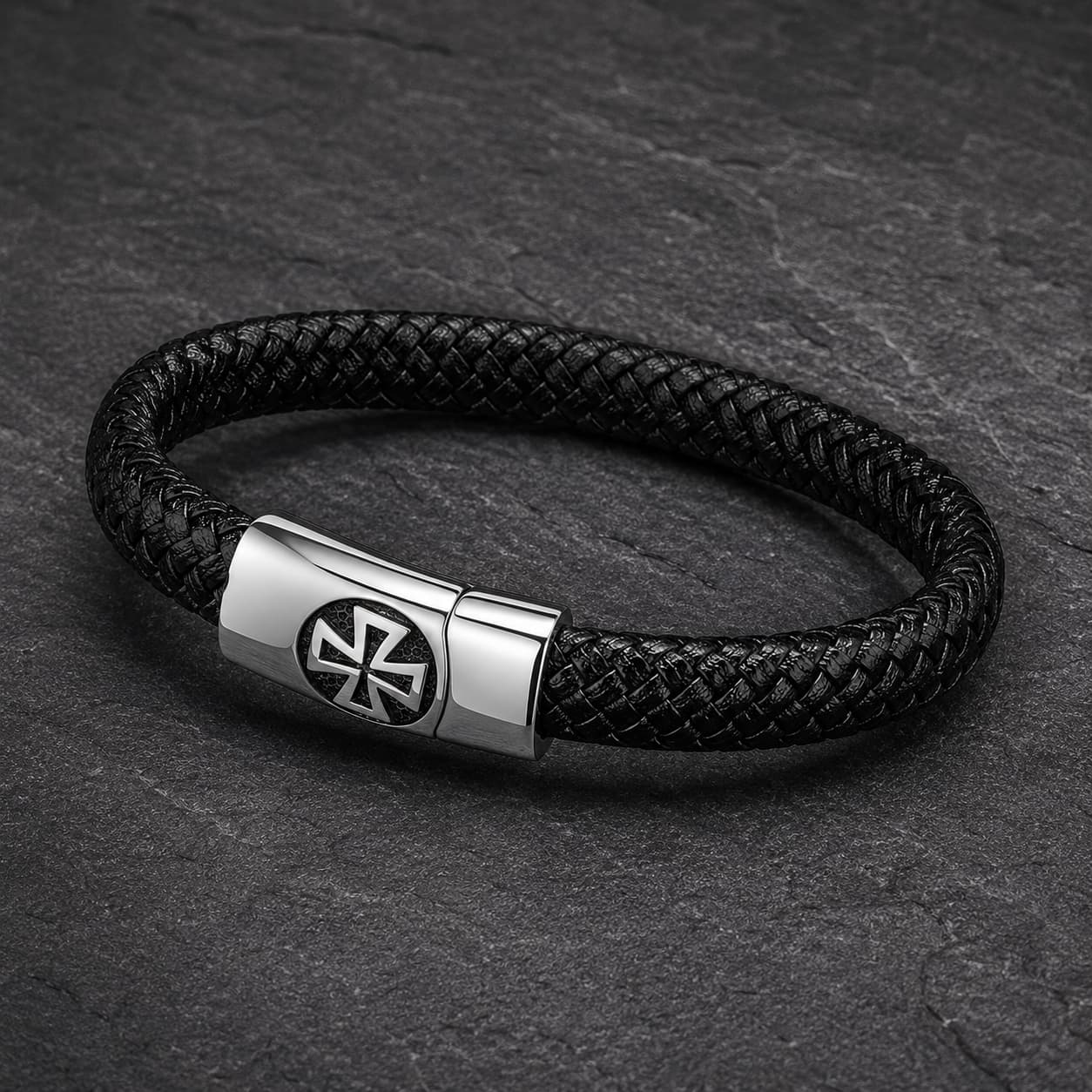 Vue angle 3/4 du Bracelet de l’Élévation en cuir tressé noir et acier inoxydable sur fond anthracite texturé