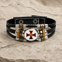 Bracelet Force du Temple en cuir tressé noir avec médaillon croix rouge et alliage métallique sur pierre médiévale claire
