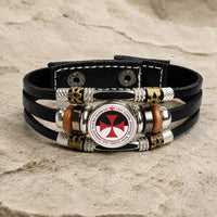 Bracelet Force du Temple en cuir tressé noir avec médaillon croix rouge et alliage métallique sur pierre médiévale claire