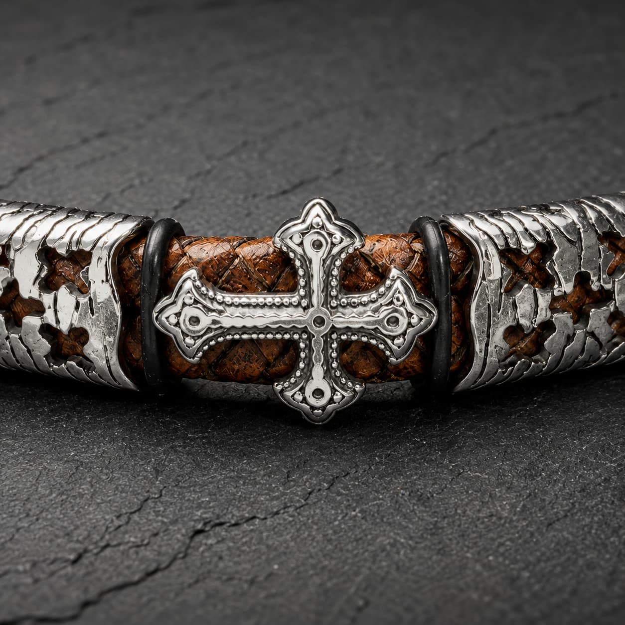 Gros plan de la croix du Bracelet de l’Indulgence en cuir tressé marron et acier inoxydable