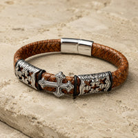 Vue angle 3/4 du Bracelet de l’Indulgence en cuir tressé marron et acier inoxydable sur pierre médiévale claire