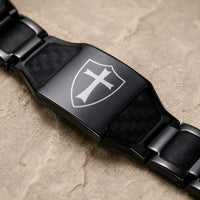 Gros plan du Bracelet Noir du Croisé avec croix bouclier et détails fibre de carbone