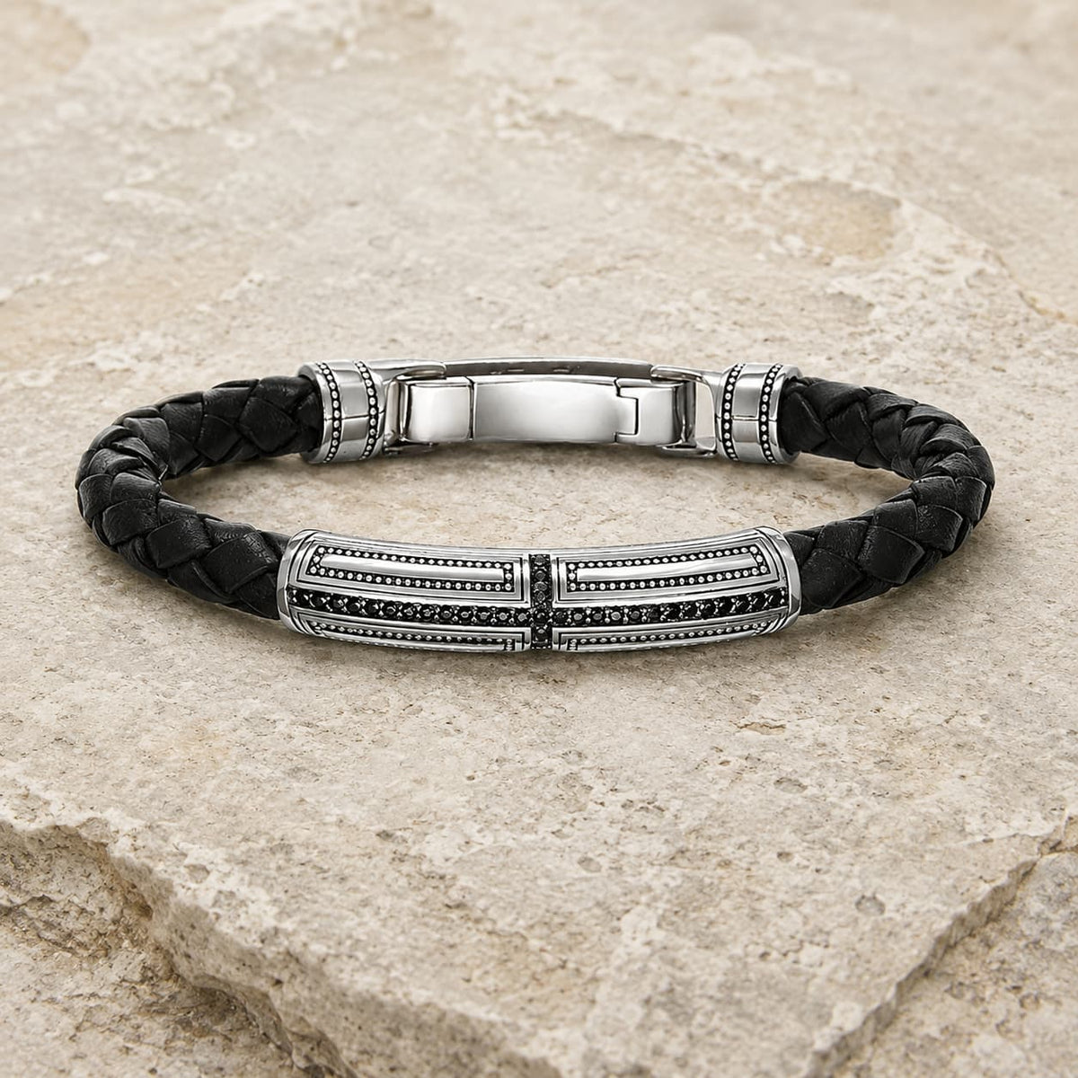 Bracelet du Primat Sacré en argent 925 sterling et cuir tressé noir présenté sur pierre médiévale claire