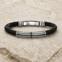 Bracelet du Primat Sacré en argent 925 sterling et cuir tressé noir présenté sur pierre médiévale claire