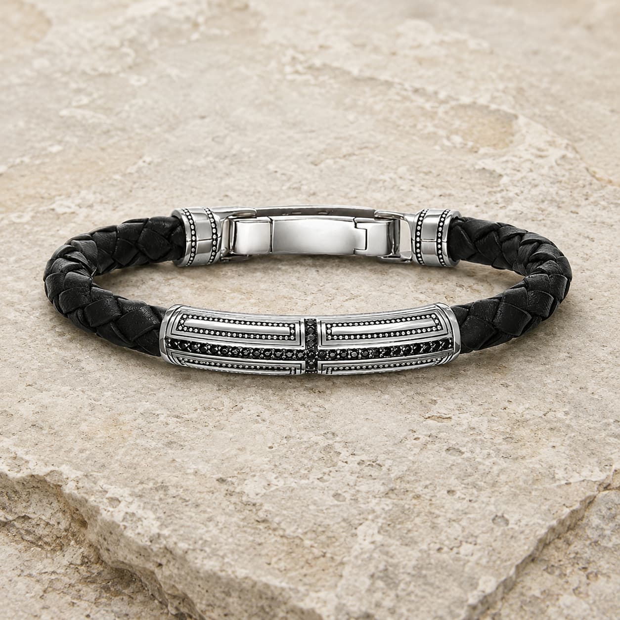 Bracelet du Primat Sacré en argent 925 sterling et cuir tressé noir présenté sur pierre médiévale claire