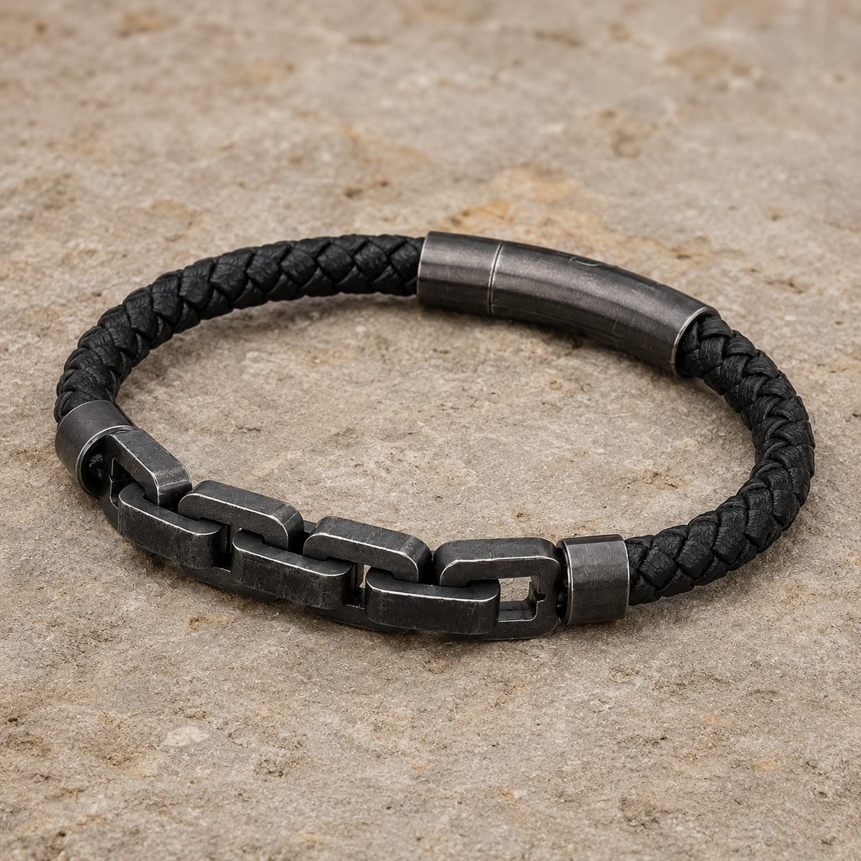 Bracelet de Robert de Craon en cuir tressé noir et acier inoxydable présenté en vue angle 3/4 sur pierre médiévale claire