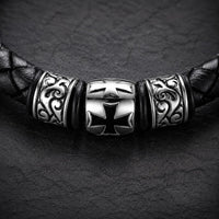 Gros plan de la croix templière du Bracelet du Templier Sage en cuir noir tressé et acier inoxydable premium
