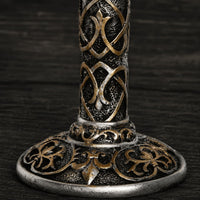 Gros plan sur la base décorée du Calice du Festin Templier avec ornements médiévaux argentés et bronze.