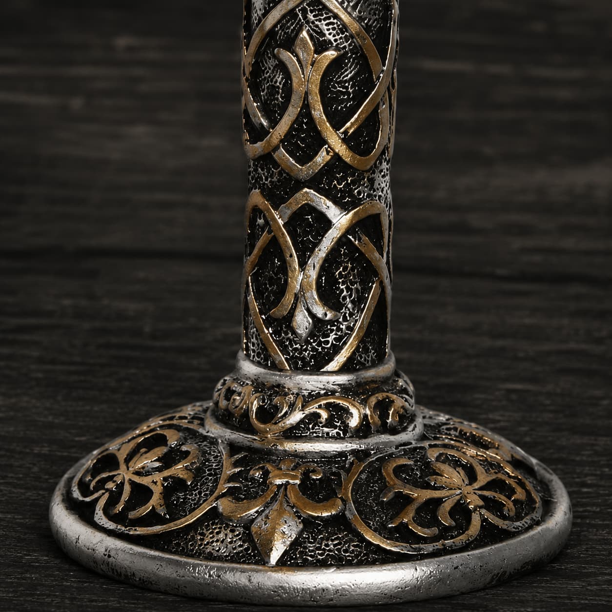 Gros plan sur la base décorée du Calice du Festin Templier avec ornements médiévaux argentés et bronze.