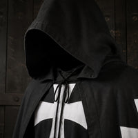 Gros plan de la Cape de la Confrérie Templière en nylon noir avec capuche, cordon et croix blanche.