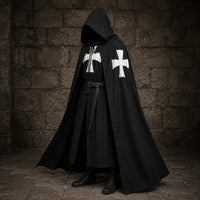 Cape de la Confrérie Templière en nylon noir portée de biais avec capuche et croix blanches sur fond de pierre sombre.