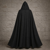 Vue arrière de la Cape de la Confrérie Templière en nylon noir sur fond de pierre médiévale claire.
