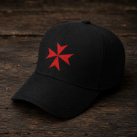 Casquette Croix de Malte en polyester et coton noir présentée sur un fond bois rustique.