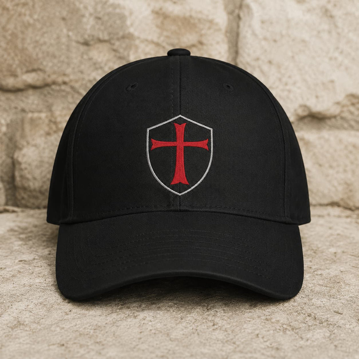 Casquette du Chevalier Templier en polyester et coton noir avec croix rouge sur fond pierre médiévale claire.