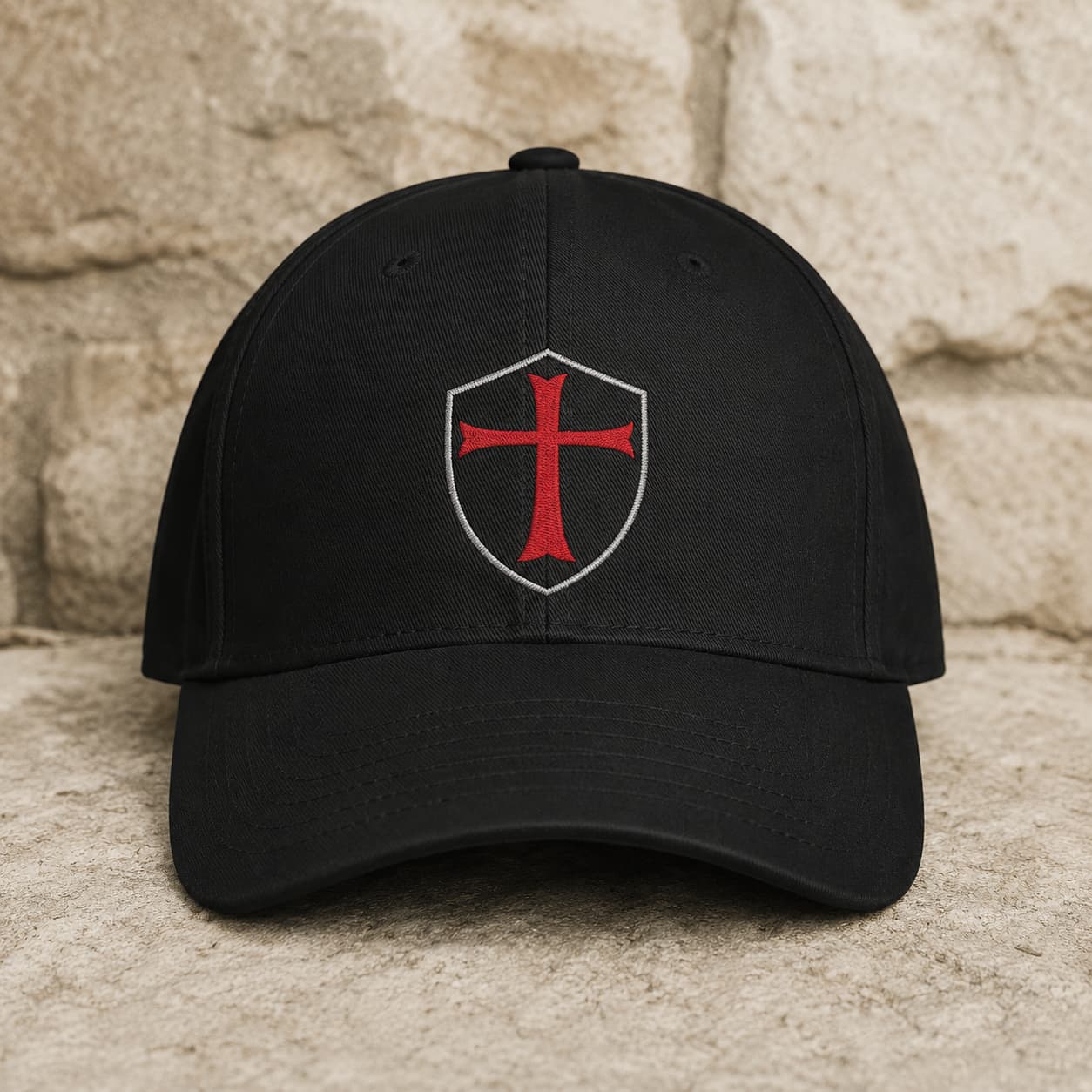 Casquette du Chevalier Templier en polyester et coton noir avec croix rouge sur fond pierre médiévale claire.